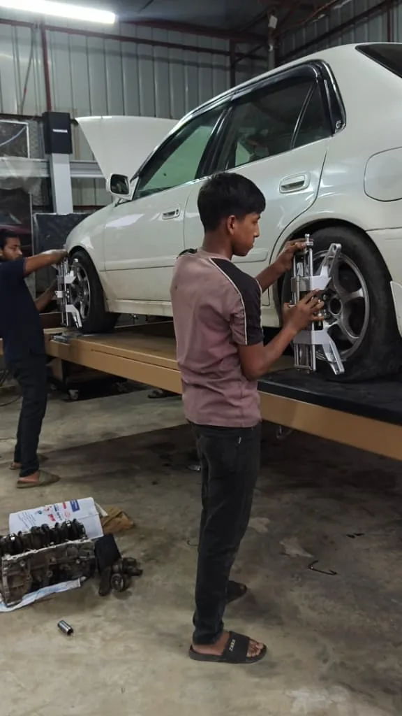 Mechanic fitting an alignment clamp to a white car's wheel.